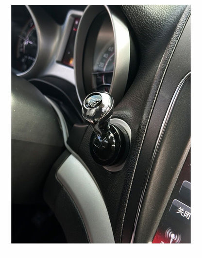 Close-up of a Car Start / Stop Button Joystick with a metallic MOMENT TEST TOP knob, surrounded by car controls and speedometer gauges—a sleek interior accessory for luxury car upgrades.